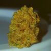 Close-up photo of a detailed, textured dried cannabis bud with visible trichomes and hints of green.