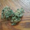 Two cannabis buds on a wooden surface.