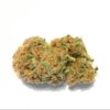 Cannabis bud with visible trichomes and orange pistils on a light-colored surface.