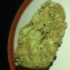 Close-up of a cannabis bud displaying a dense structure with vibrant green hues and orange pistils.